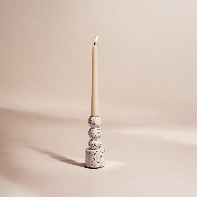 Terrazzo candle holder with a lit candle on a beige background