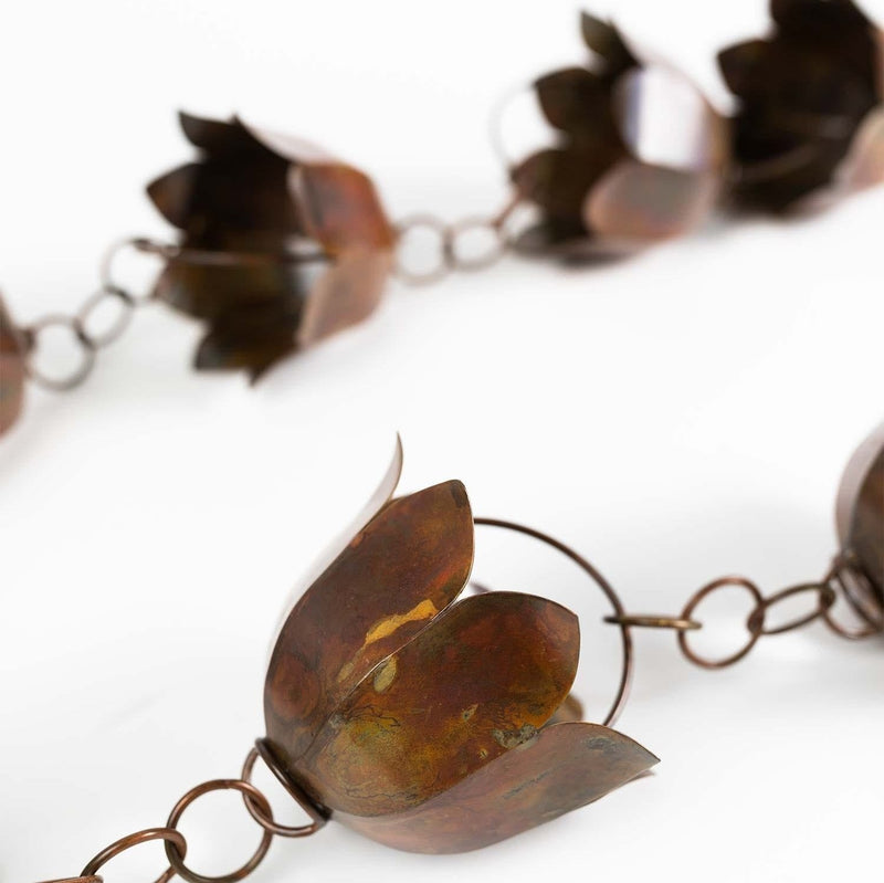 Close-up of an iron rain chain with lotus-shaped cups on a chain.