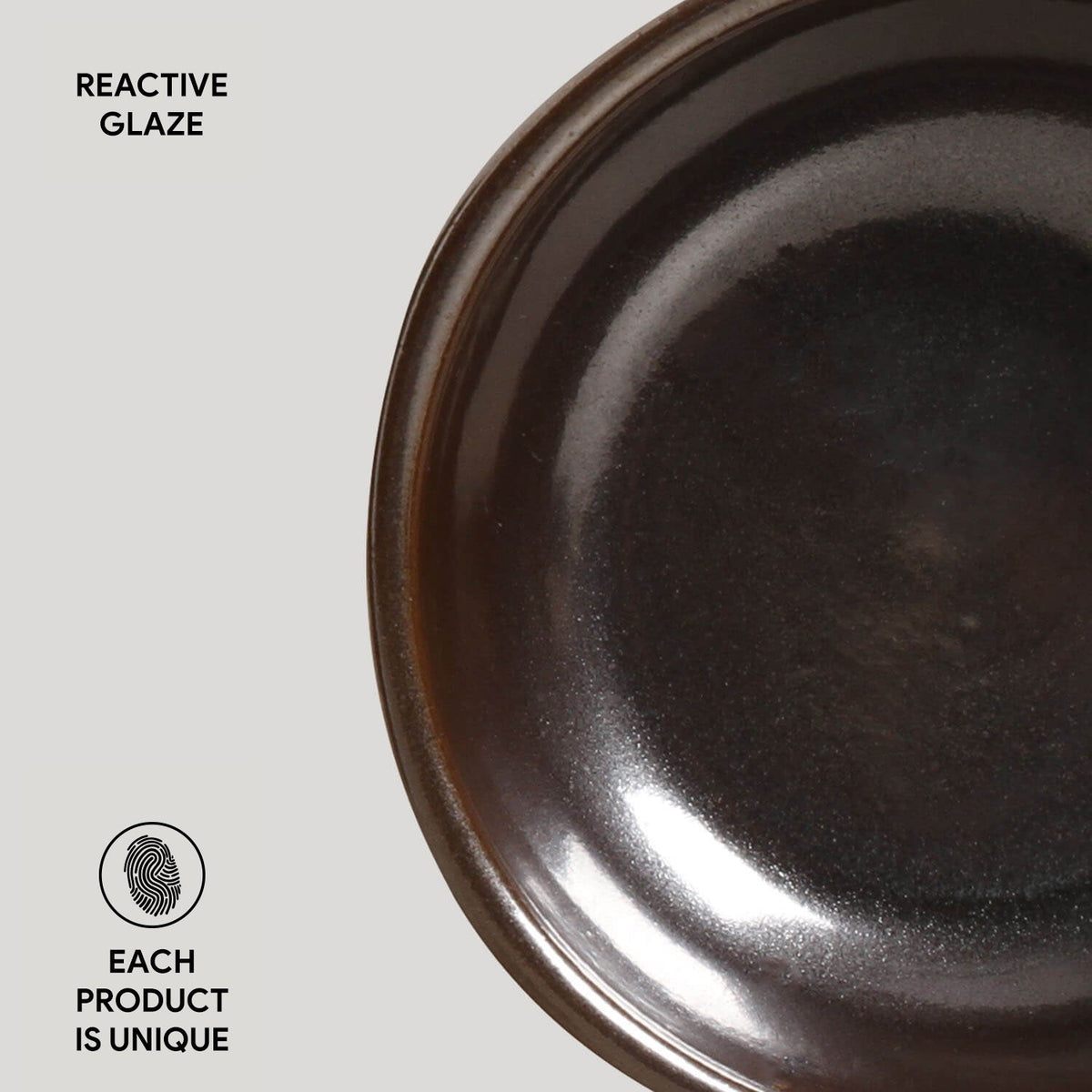 Close-up of a dark ceramic plate with 'Reactive Glaze' text and 'Each Product is Unique' label on a light gray background.