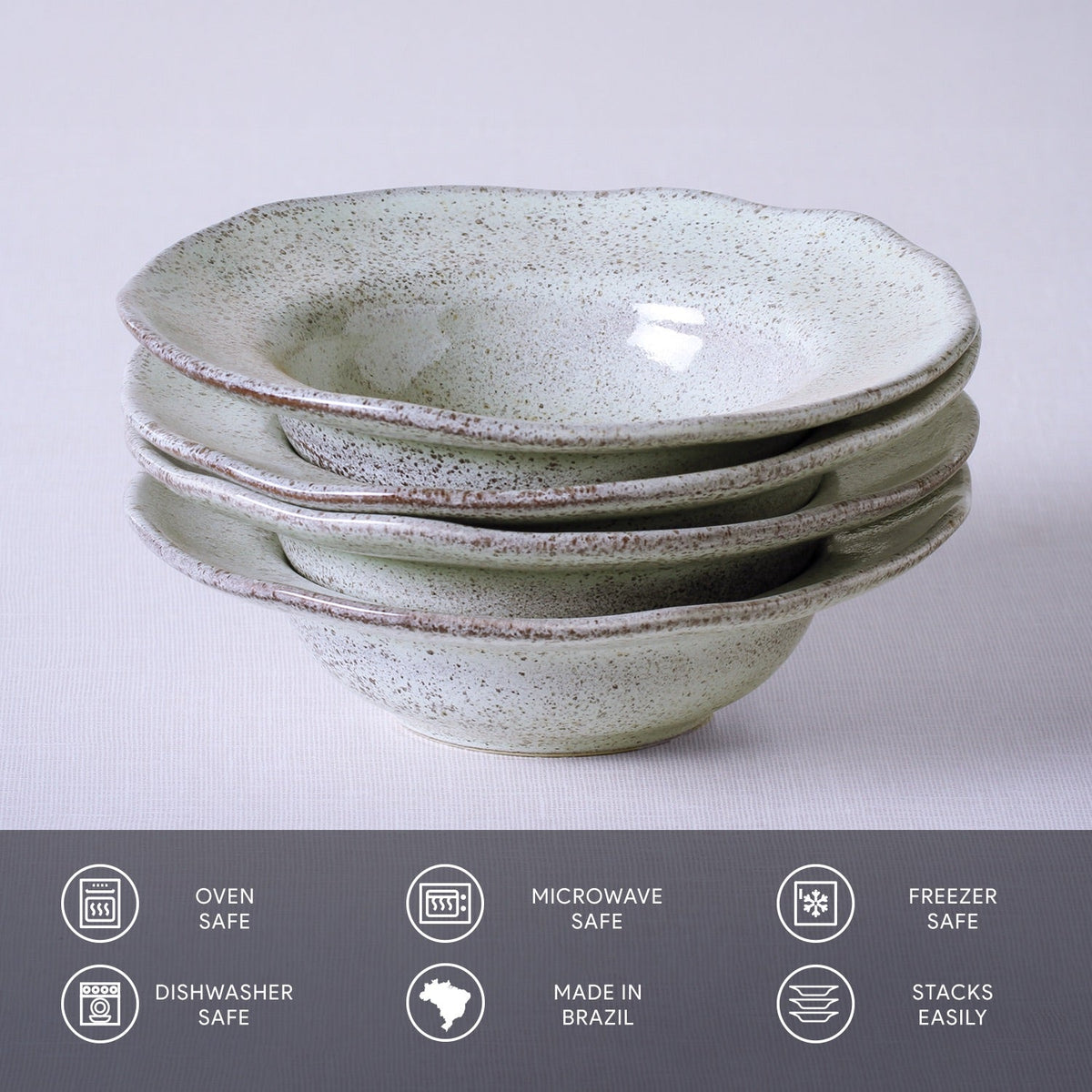 Stack of ceramic bowls with speckled texture on a light gray background