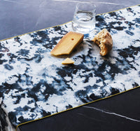 Cheese and crackers on a marble table runner with a glass of water