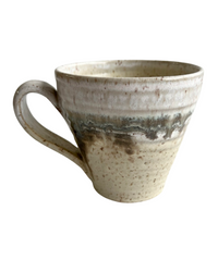 Ceramic mug with light and dark neutral glaze details on a white background