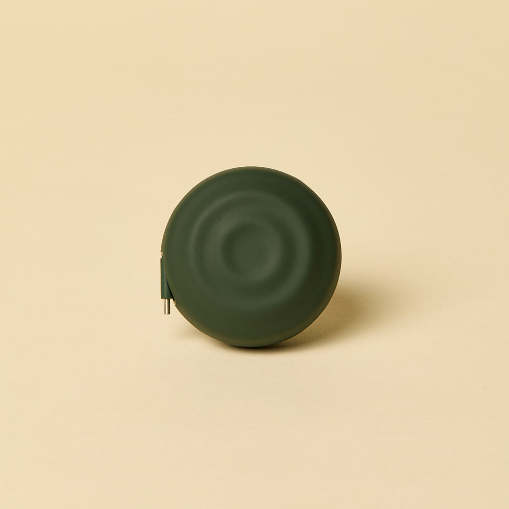 Green spherical object with a charging cord on a beige background