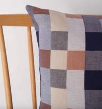 Plaid patterned pillow on a wooden chair against a white background