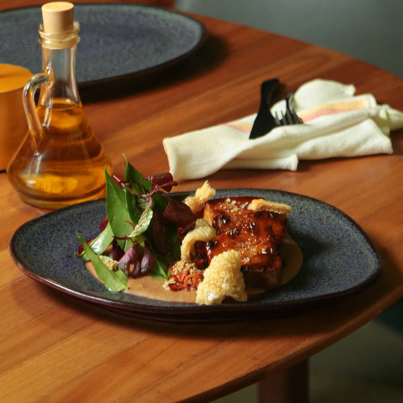 Plated dish with fried food and salad on a wooden table with a bottle of oil.