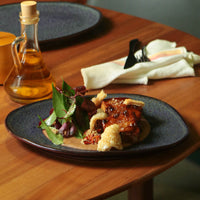 Plated dish with fried food and salad on a wooden table with a bottle of oil.