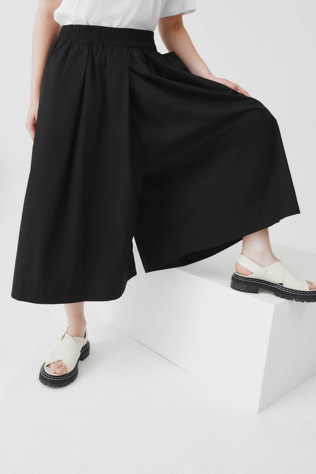 Person wearing black wide-leg culottes on a white background