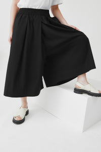 Person wearing black wide-leg culottes on a white background