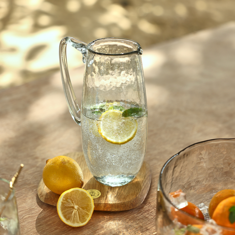 Pebbled Glass Pitcher with fruit infused water on a table outside