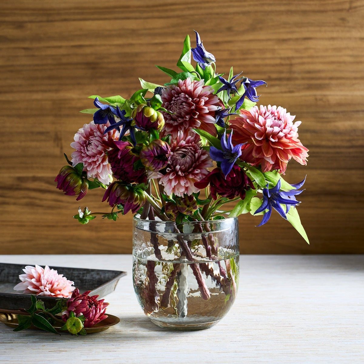 Bouquet of flowers in a clear vase on a wooden surface with a wooden background