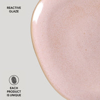 Close-up of a pink ceramic plate with reactive glaze on a light gray background