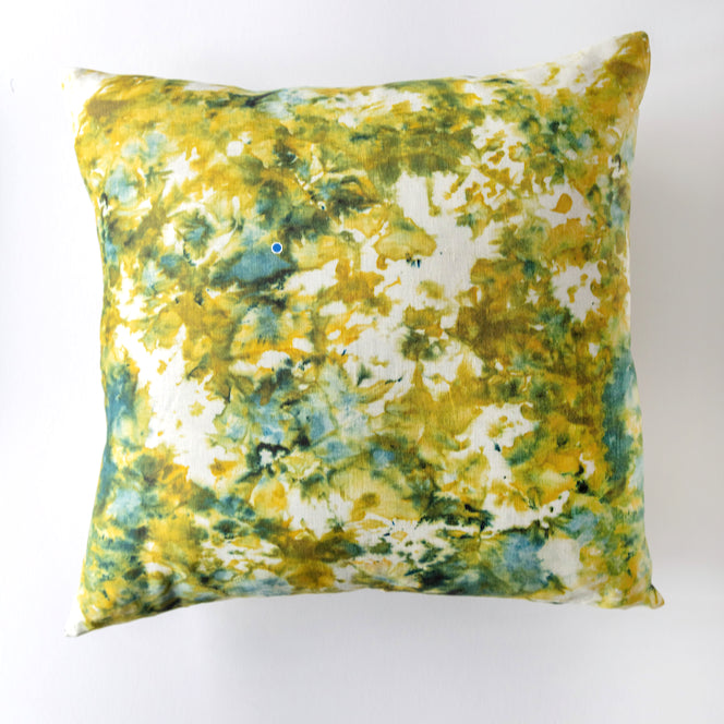Decorative pillow with a yellow and green abstract pattern on a white background