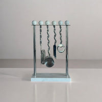 Metallic bar utensil set on a stand with a neutral background