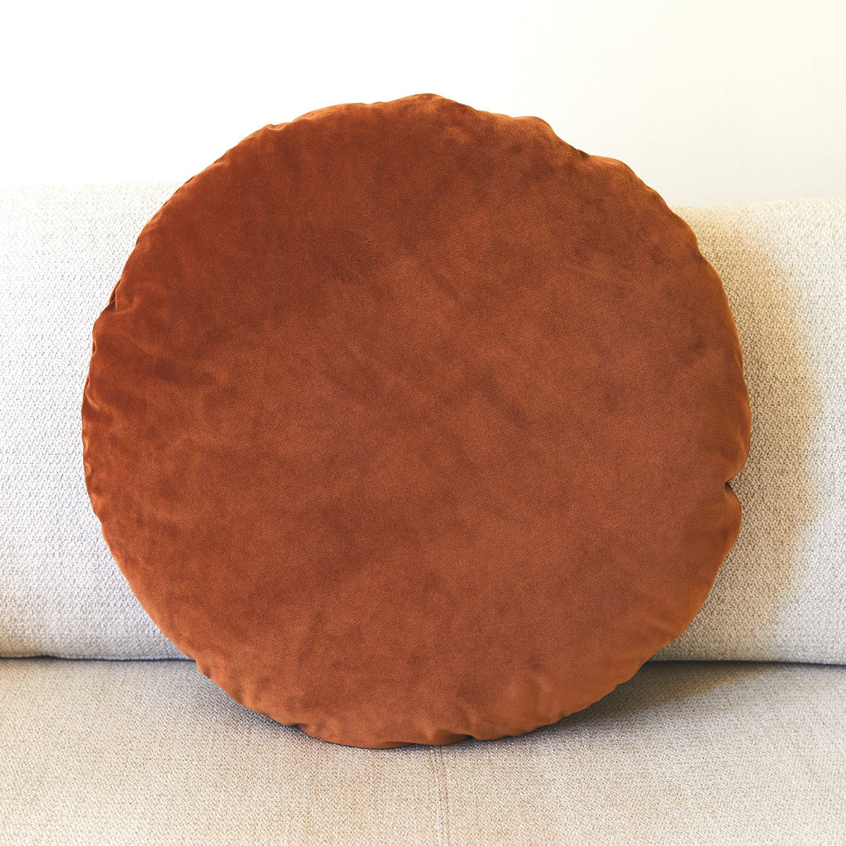 Round brown cushion on a beige sofa
