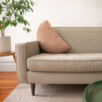 Beige sofa with a brown pillow in a living room setting