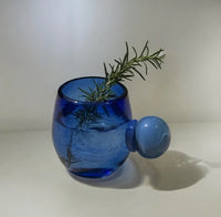 Blue glass cup with a rosemary sprig and drink on a white background