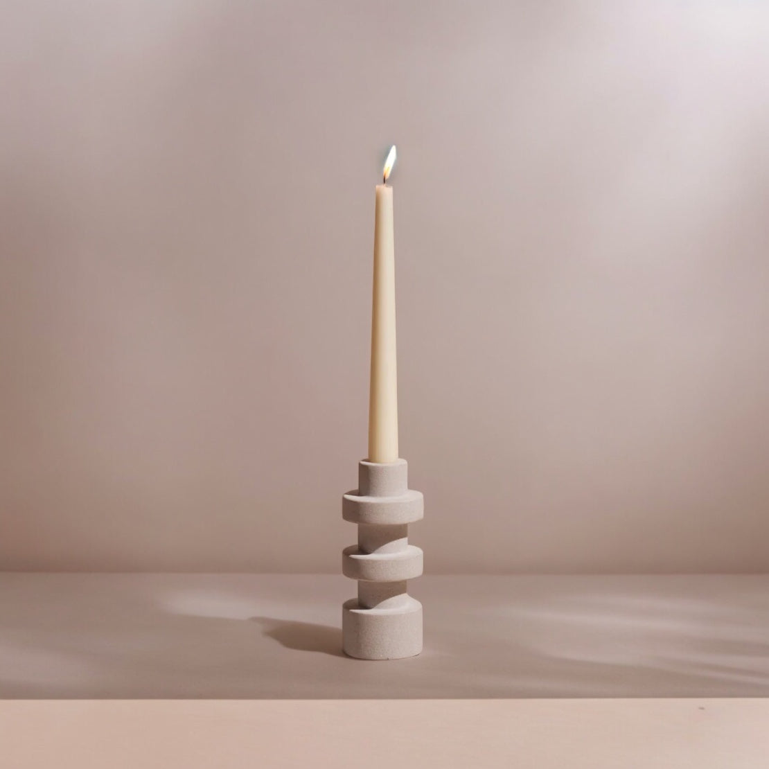 Sandstone candle holder with a lit candle on a neutral background