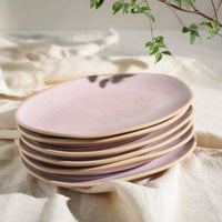 Stack of ceramic plates with a soft pink hue on a light fabric background