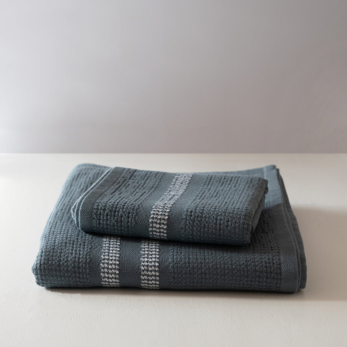 Folded blue textured towels on a white surface