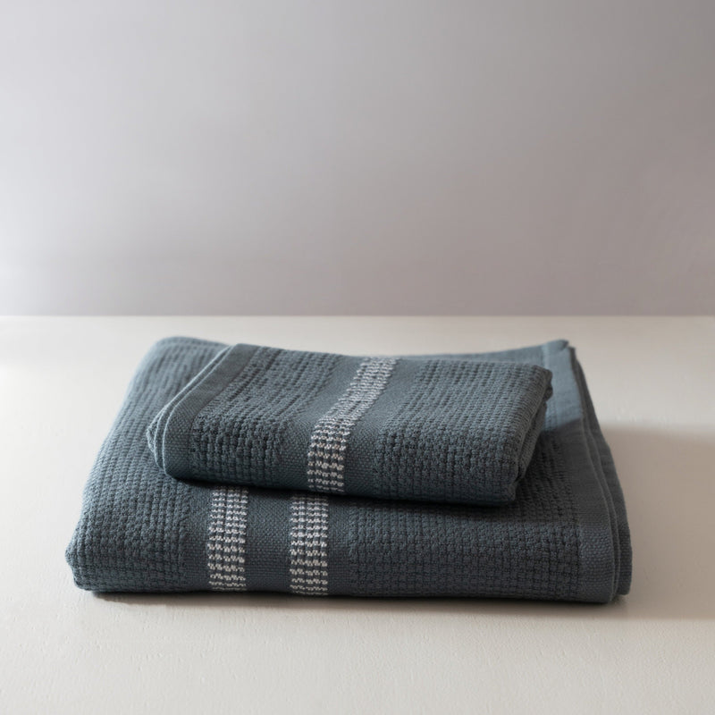Folded blue textured towels on a white surface