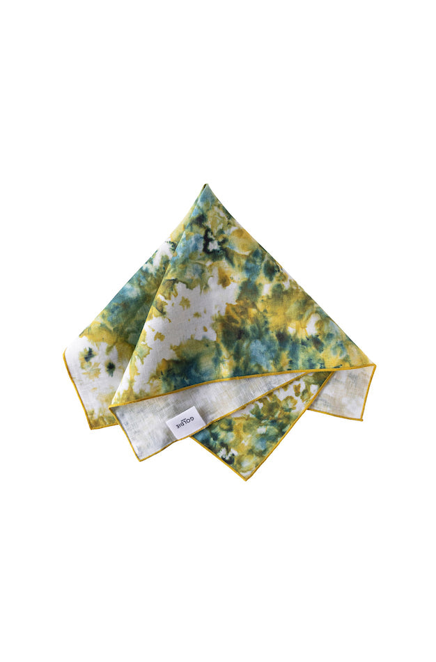 Tie-dye napkin with green and yellow pattern on a white background