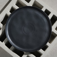 Black ceramic plate on a textured concrete surface