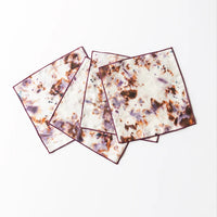 Four square cocktail napkins with a marble-like design on a white background