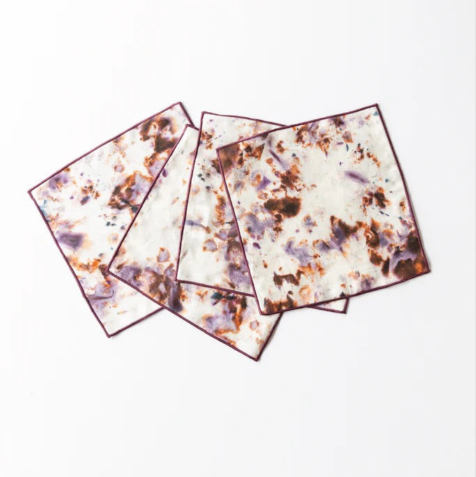 Four square cocktail napkins with a marble-like design on a white background
