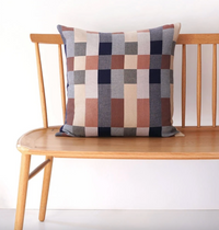 Checkered pillow on a wooden bench against a white background