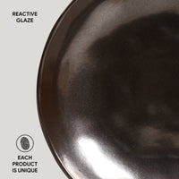 Close-up of a dark, textured ceramic bowl with 'Reactive Glaze' text and 'Each Product is Unique' label.