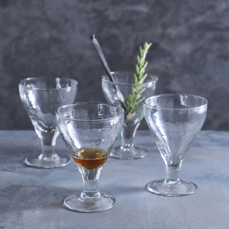 Set of clear glass goblets on a gray surface with a dark background