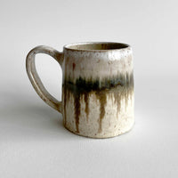Ceramic mug with light and dark neutral glaze details on a white background