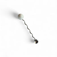 stainless steel squiggle beverage stirrer on white background