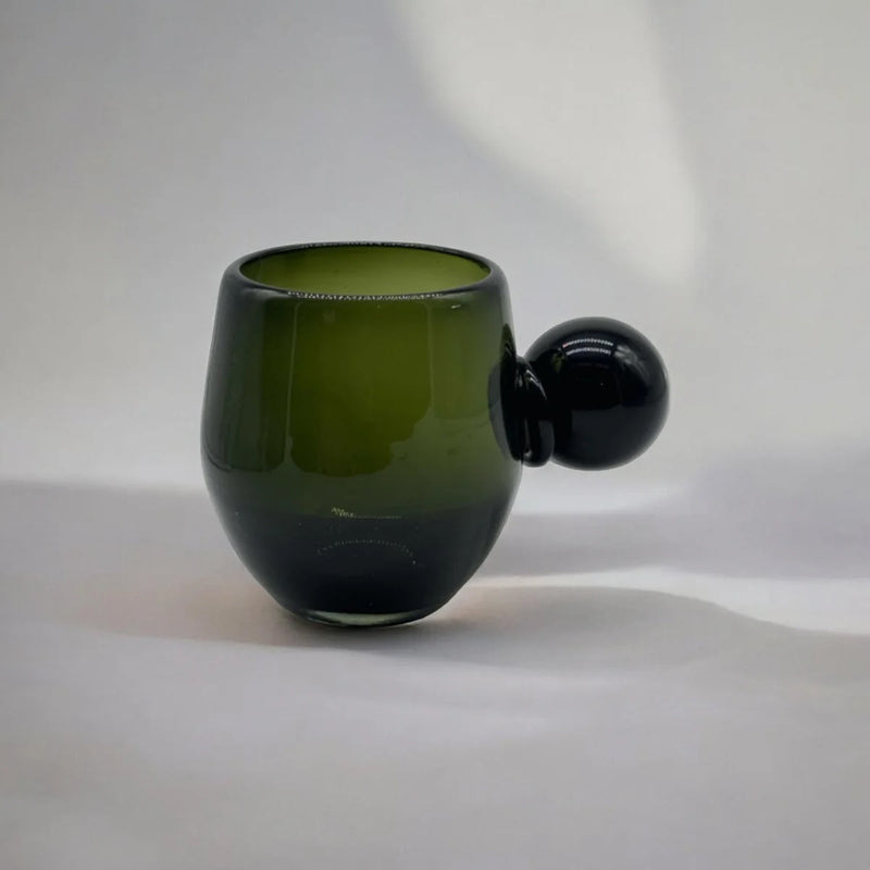 Green glass cup with a spherical handle on a white background