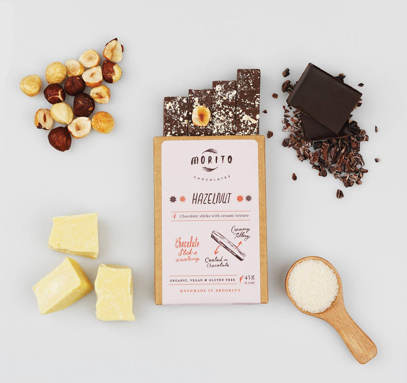 Morito chocolate bars with ingredients including hazelnuts, chocolate pieces, and a scoop of sugar on a light background