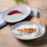 Dish of food on a wooden table with a gray plate and red pepper.