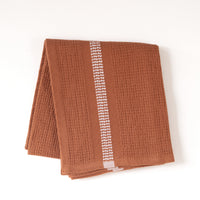 Rust color textured hand towel with a white stripe