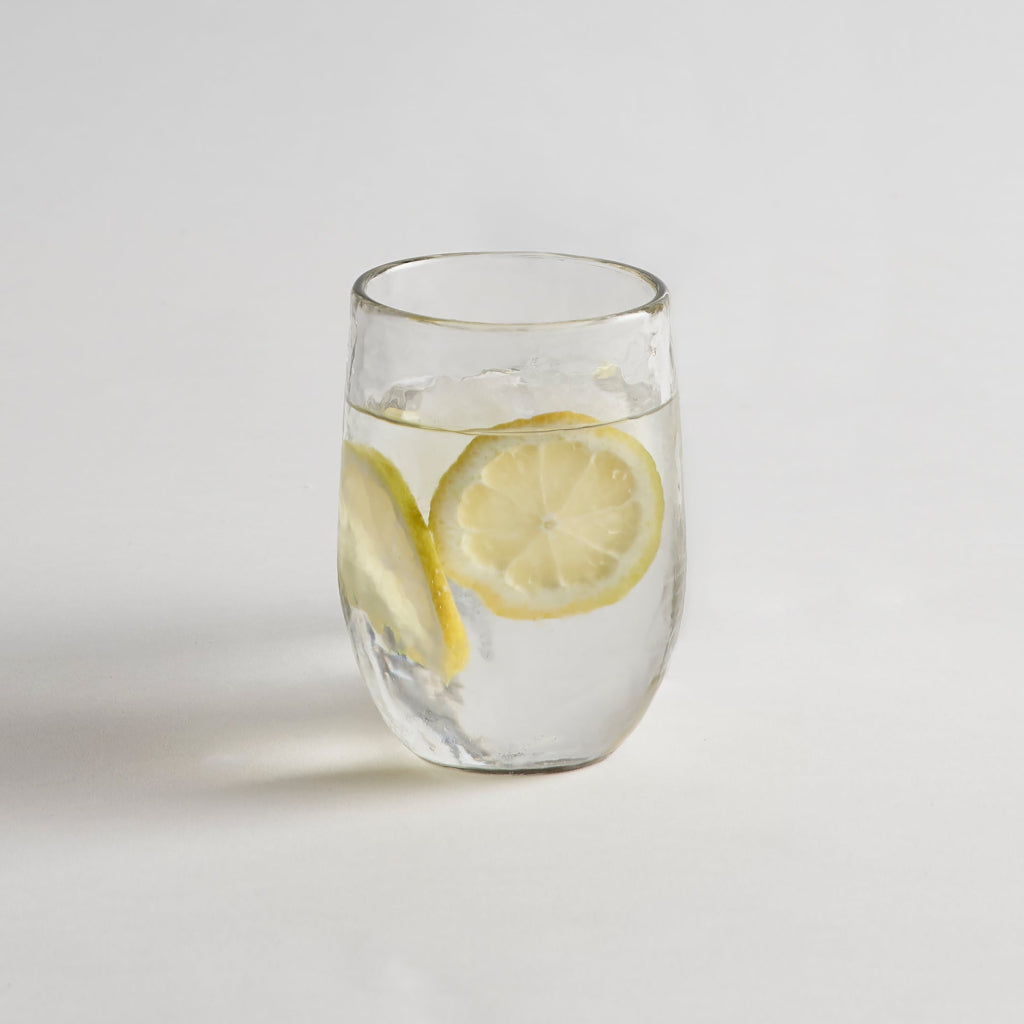 drinking glass with lemon water on a white background