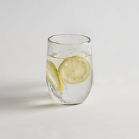 drinking glass with lemon water on a white background