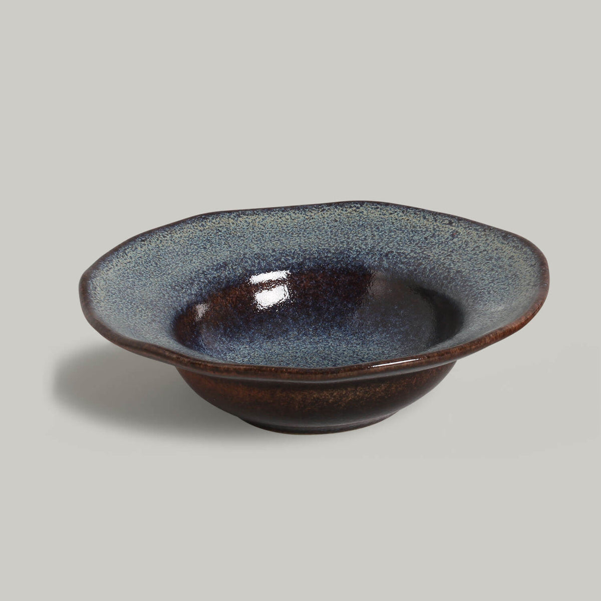 Ceramic bowl with a speckled glaze on a gray background
