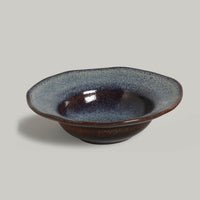 Ceramic bowl with a speckled glaze on a gray background