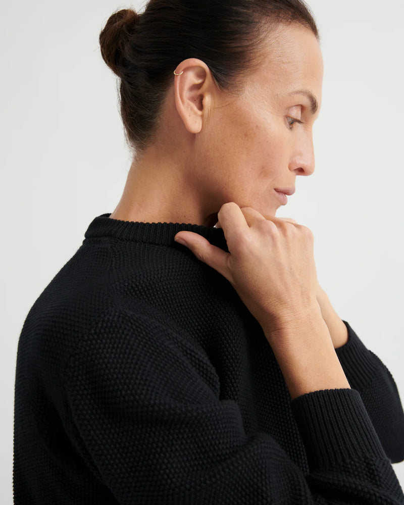 Woman wearing a black sweater against a light background