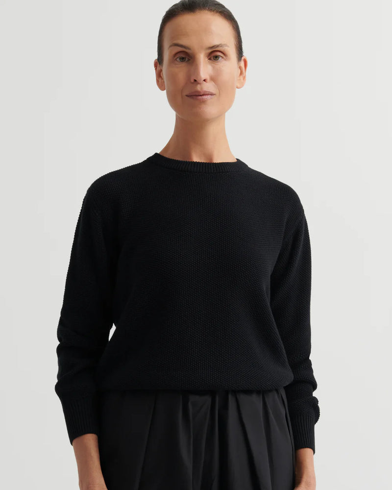 Person wearing a black sweater against a plain background