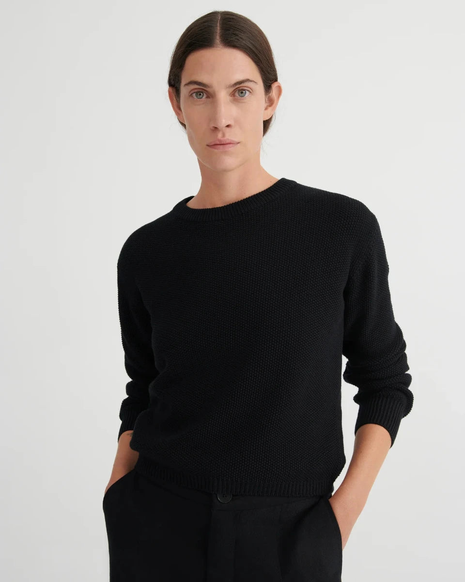 Person wearing a black sweater against a plain background