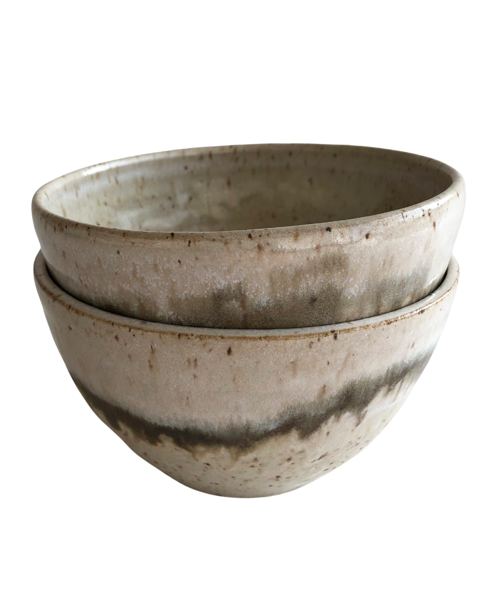 Stack of two ceramic bowls with light and dark neutral glaze details on a white background