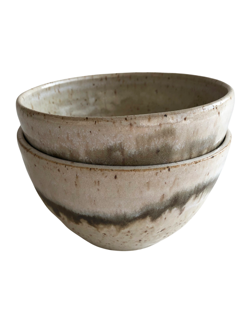 Stack of two ceramic bowls with light and dark neutral glaze details on a white background