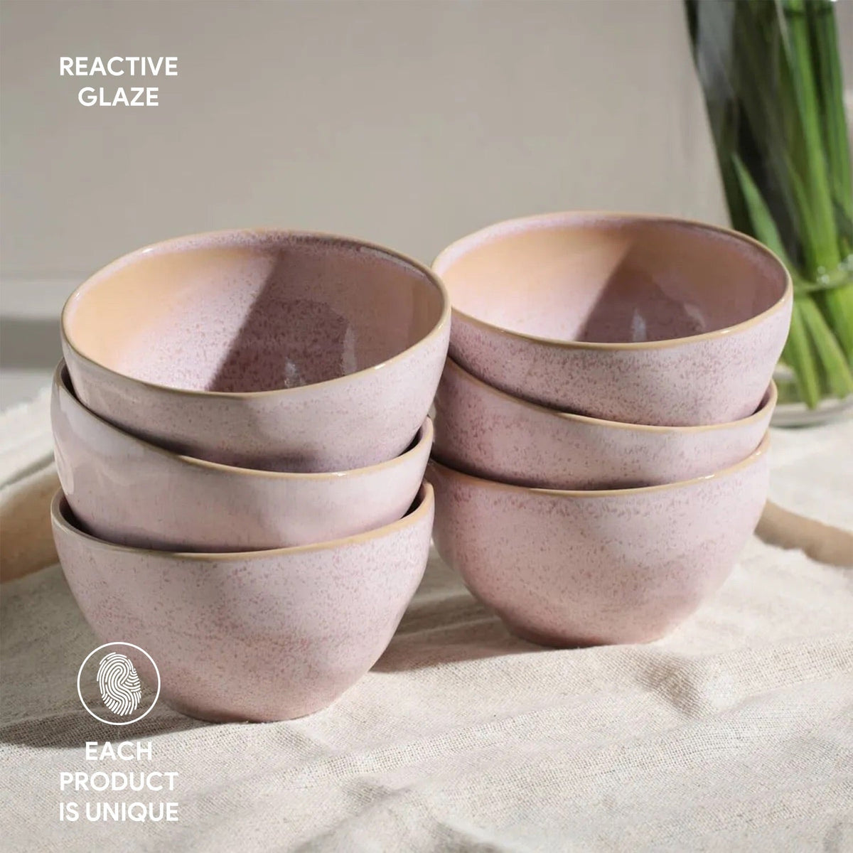 Set of pink ceramic bowls with reactive glaze on a light surface.