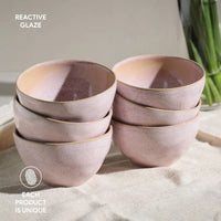 Set of pink ceramic bowls with reactive glaze on a light surface.