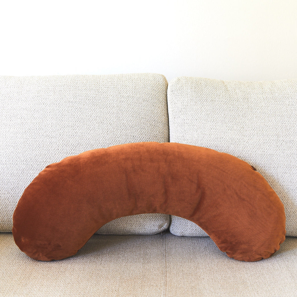 Brown U-shaped pillow on a light gray sofa