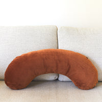 Brown U-shaped pillow on a light gray sofa